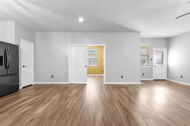 a view of a big room with wooden floor and a kitchen