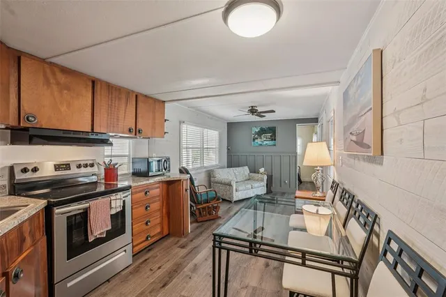 a kitchen with stainless steel appliances granite countertop a stove a sink dishwasher and white cabinets with wooden floor