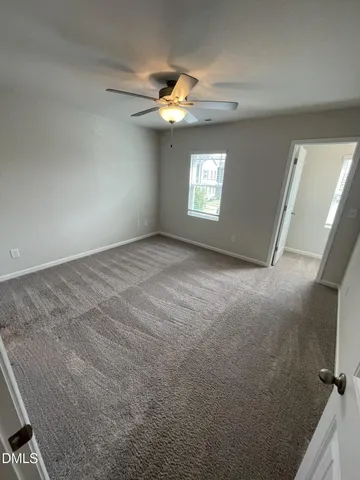 en empty room with windows and chandelier fan