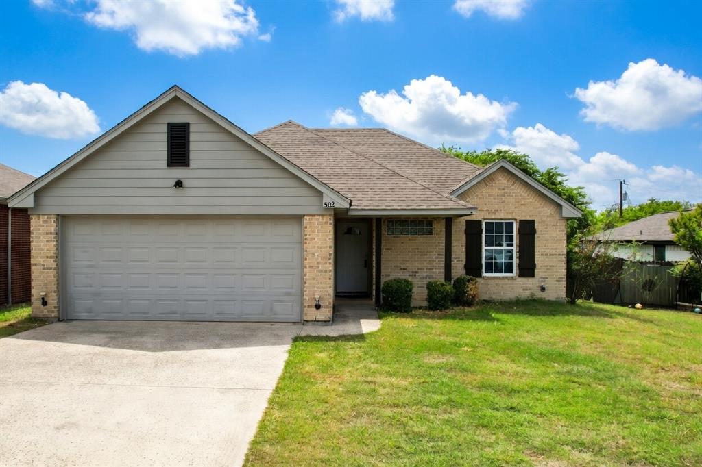 a front view of house with yard and trees in the background