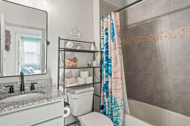 a bathroom with a granite countertop bathtub sink vanity mirror and toilet