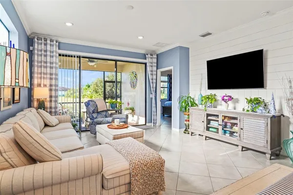 a living room with furniture a flat screen tv and floor to ceiling window