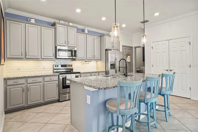 a kitchen with stainless steel appliances granite countertop a sink a stove a refrigerator and chairs