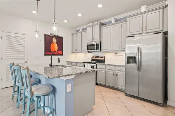 a kitchen with stainless steel appliances granite countertop a refrigerator a sink a stove a dining table and chairs