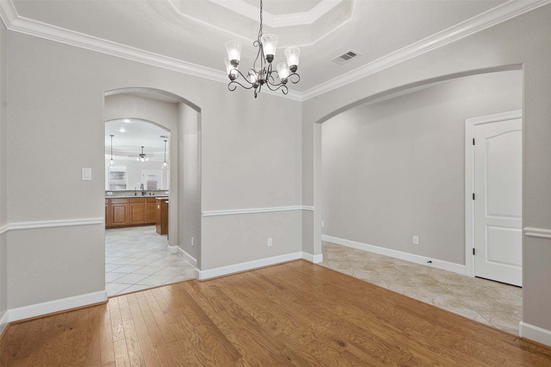 721 Rufina Street League City, TX 77573 - Photo 5 of 33 Another view showcases the dining room's impressive architectural details, including the tray ceiling, decorative molding, and seamless connection to both the foyer and kitchen. The open design enhances everyday convenience while preserving a sense of formal elegance.