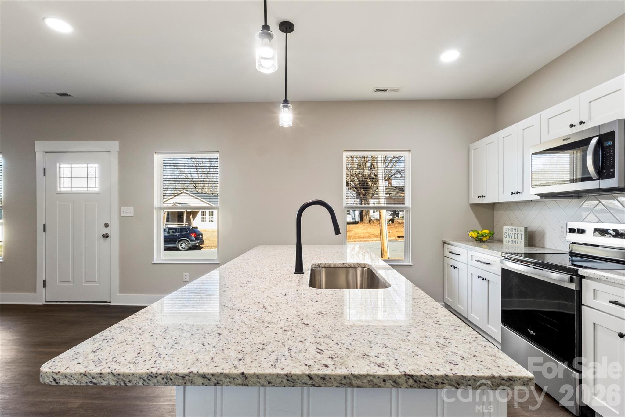 316 Union Street Maiden, NC 28650 - Photo 7 of 23 a kitchen with kitchen island granite countertop a stove a sink a refrigerator and a dining table with wooden floor