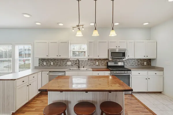 a kitchen with kitchen island granite countertop a stove a sink a center island and wooden floor