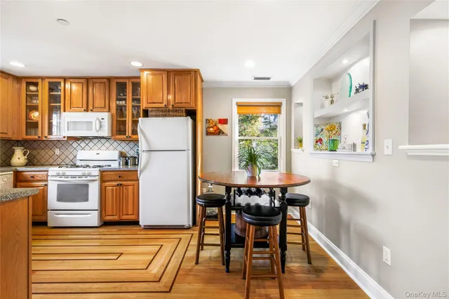 a kitchen with stainless steel appliances granite countertop a refrigerator a stove a microwave oven with a dining table and chairs with wooden floor