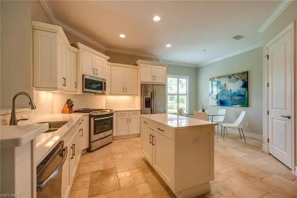 a large kitchen with stainless steel appliances granite countertop a stove top oven a sink a dining table and chairs