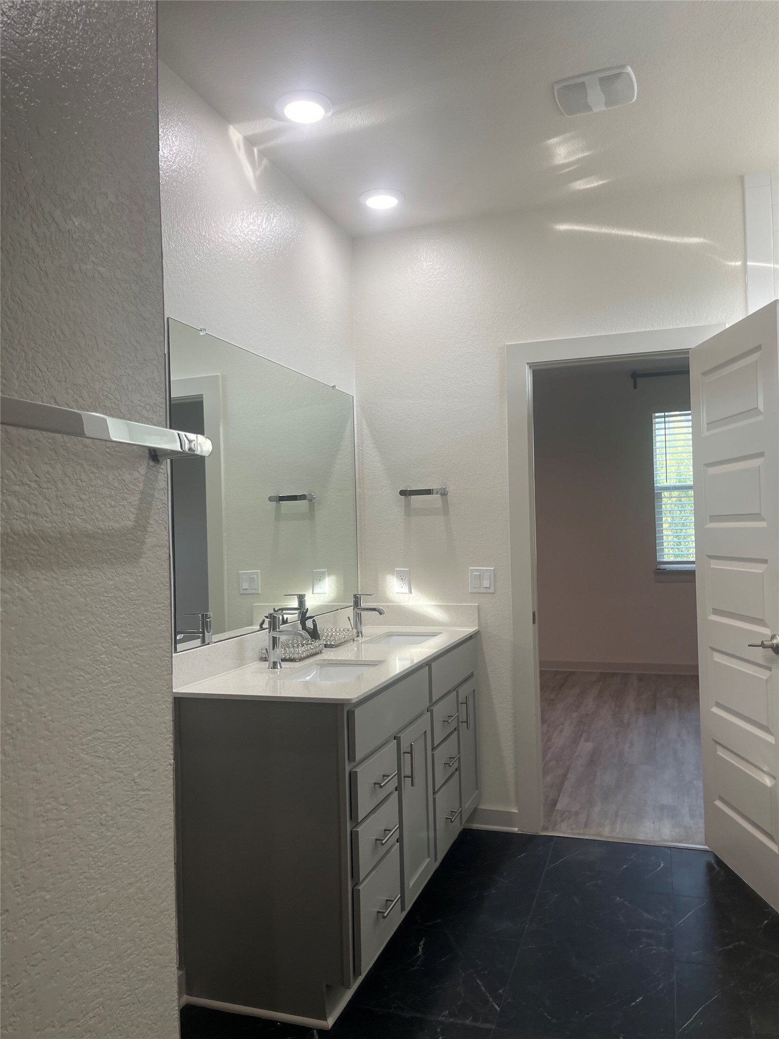 145 Merrick Road Georgetown, TX 78628 - Photo 16 of 32 Recessed lighting illuminates a modern double vanity topped with stone counters and dual mirrors.
