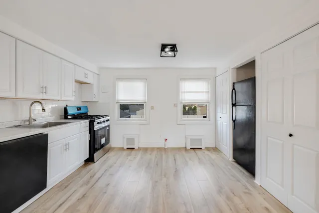 a kitchen with cabinets wooden floor and stainless steel appliances