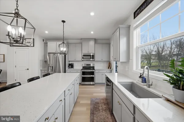 a large kitchen with a counter space a sink appliances and living room view