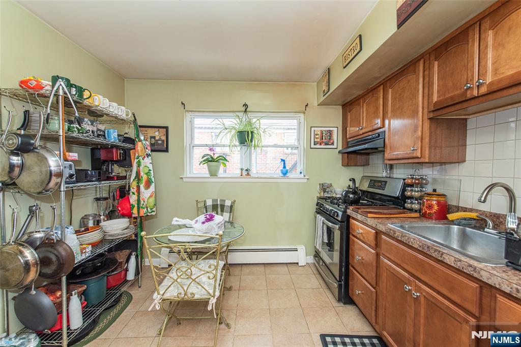 233 9th Street Fairview, NJ 07022 - Photo 3 of 7 a kitchen with stainless steel appliances granite countertop a sink dishwasher and cabinets with wooden floor