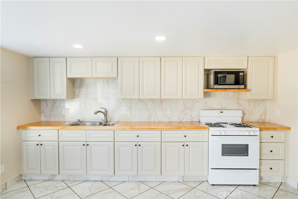 11711 Carmine Street Riverside, CA 92505 - Photo 25 of 33 a kitchen with white cabinets stainless steel appliances and sink