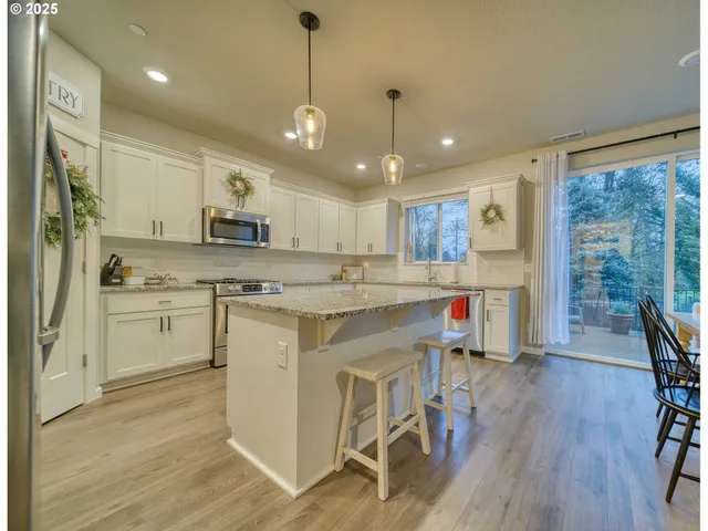 a kitchen with white cabinets stainless steel appliances and wooden floor