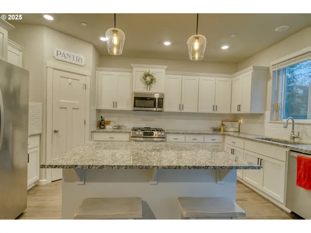 a kitchen with kitchen island granite countertop a sink cabinets and stainless steel appliances