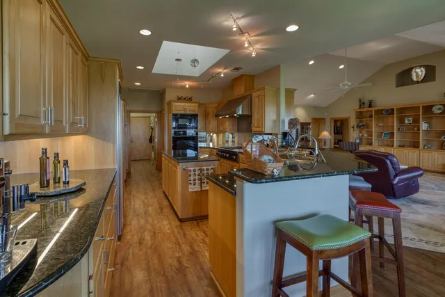 a kitchen with stainless steel appliances kitchen island granite countertop a table chairs in it and a wooden floors