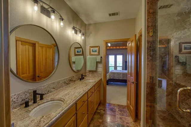 a bathroom with a granite countertop double vanity sink and a mirror