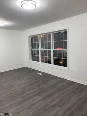 a view of an empty room with wooden floor and windows