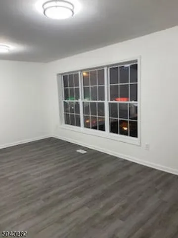 a view of an empty room with wooden floor and windows