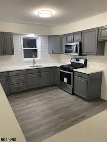 a kitchen with stainless steel appliances granite countertop a stove top oven a sink dishwasher and a microwave oven on the blue countertops with wooden floor