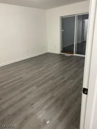an empty room with wooden floor and mirror