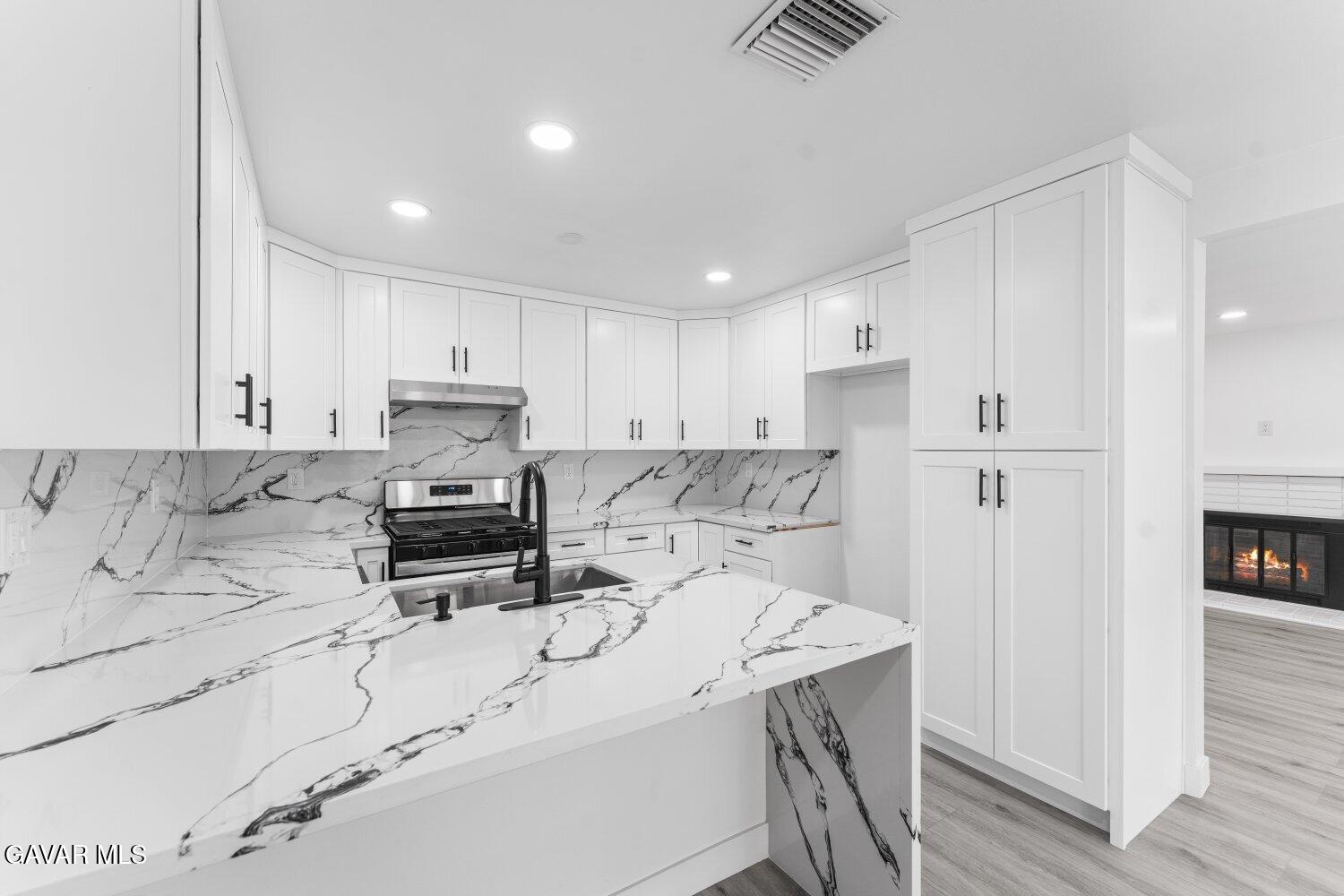 12338 Sheldon Street Sun Valley, CA 91352 - Photo 13 of 60 a kitchen with a sink a stove a refrigerator and white cabinets