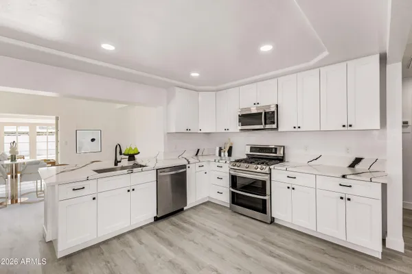 a kitchen with stainless steel appliances granite countertop a sink a stove a refrigerator cabinets and a dining table