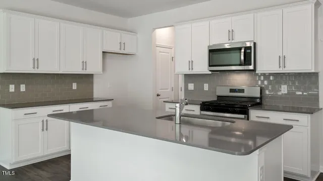 a kitchen with stainless steel appliances granite countertop a sink a stove a microwave and cabinets