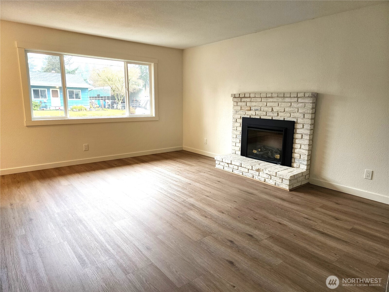 103 Kraft Road Longview, WA 98632 - Photo 2 of 19 an empty room with wooden floor fireplace and windows