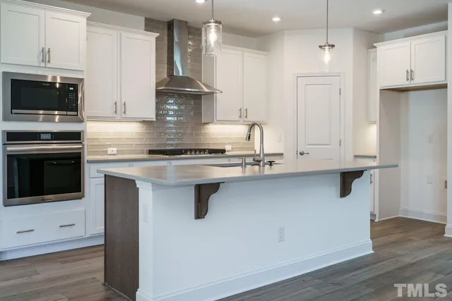 a kitchen with stainless steel appliances granite countertop a sink a stove and a refrigerator