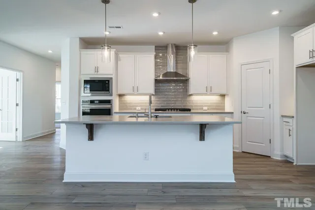 a large kitchen with stainless steel appliances kitchen island granite countertop a stove a refrigerator and a sink