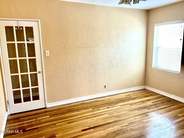a view of an empty room with wooden floor and a window