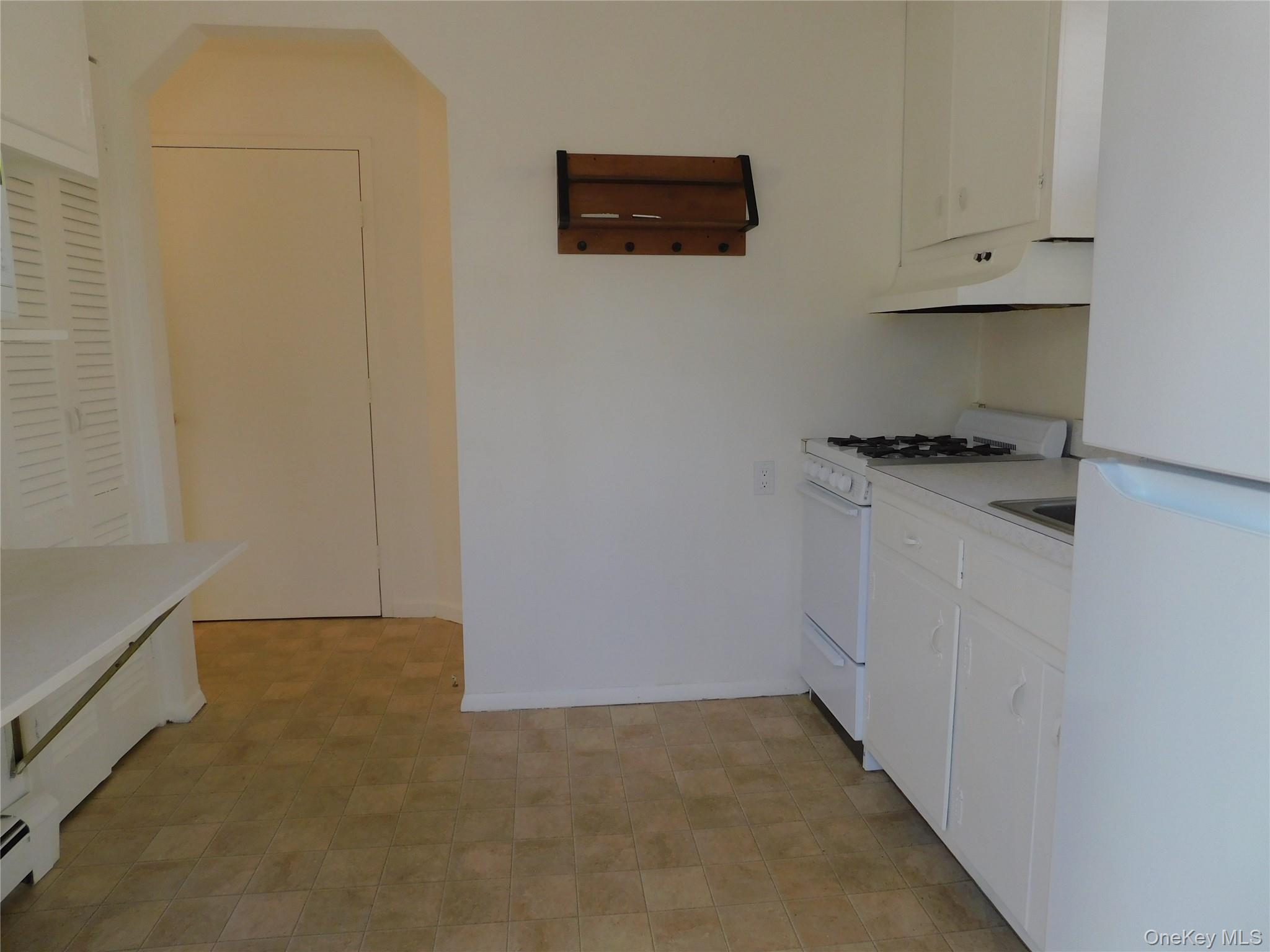 111 Lakeside Trail, Unit A Ridge, NY 11961 - Photo 7 of 8 a kitchen with white cabinets and a stove