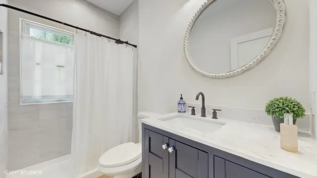 a bathroom with a granite countertop sink a toilet and a mirror