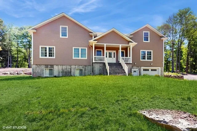 a front view of a house with a yard and trees