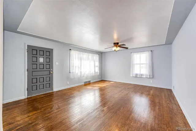 a view of an empty room with a window and wooden floor
