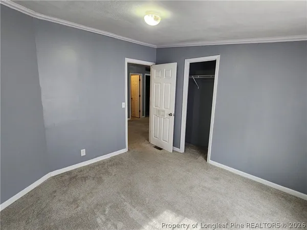 a view of an empty room with closet and a window