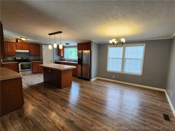 an open kitchen with granite countertop wooden floor stainless steel appliances and dining table