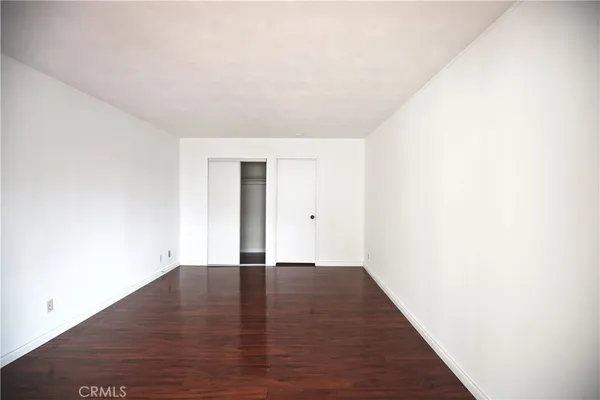 a view of an empty room with wooden floor and a fireplace