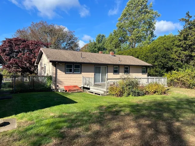 a front view of house with yard and trees in the background