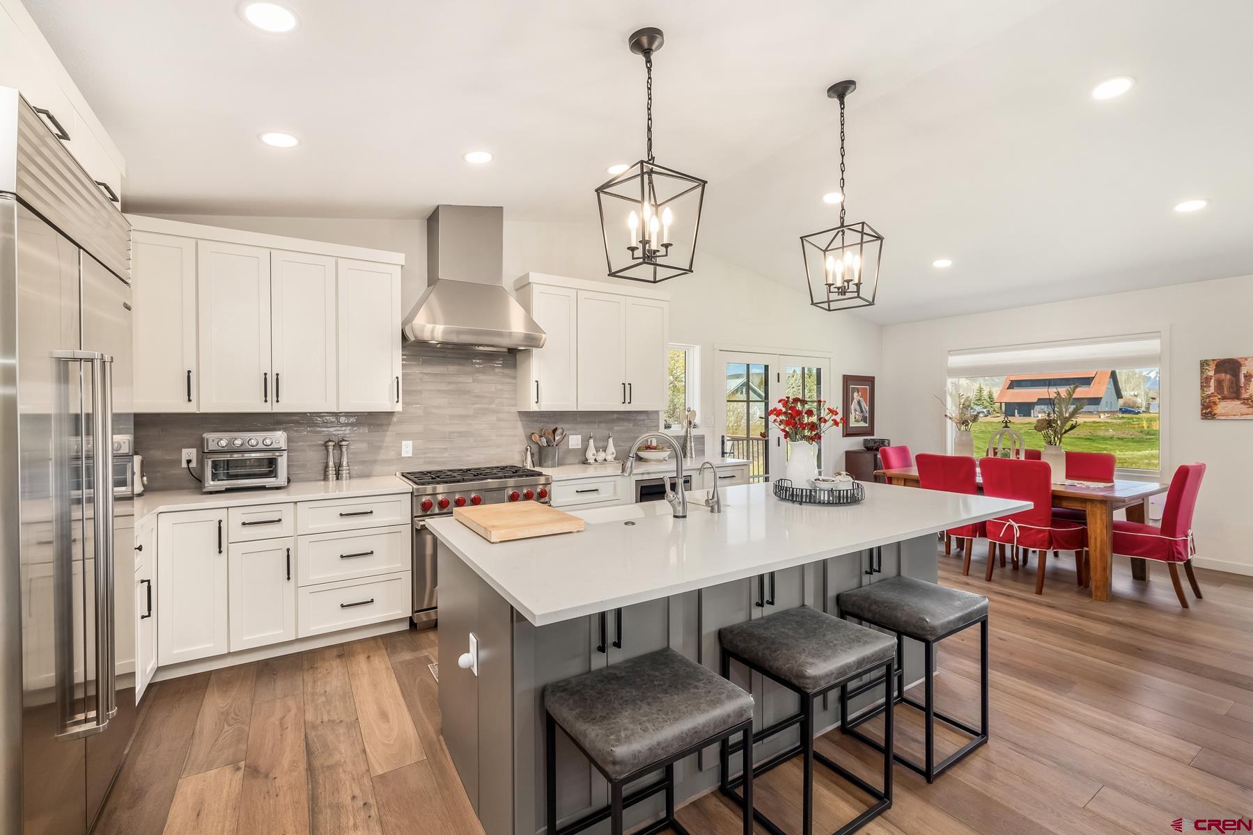389 Apache Road Gunnison, CO 81230 - Photo 11 of 43 a kitchen with stainless steel appliances a stove a sink a dining table and chairs with wooden floor
