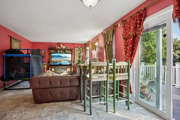 a living room with furniture a flat screen tv and a floor to ceiling window
