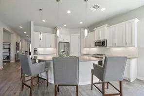 a kitchen with stainless steel appliances kitchen island granite countertop a dining table chairs refrigerator and microwave