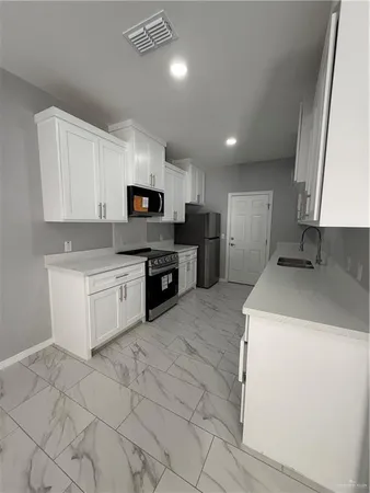 a kitchen with a sink a stove top oven and cabinets
