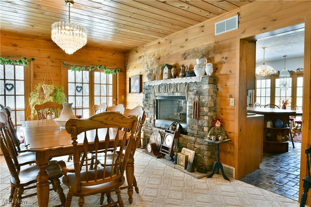 3339 Bushnell Campbell Road Fowler, OH 44418 - Photo 16 of 50 Dining area with wood ceiling, wooden walls, visible vents, and a chandelier