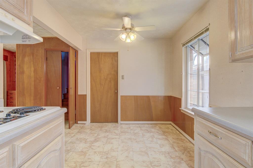 9203 Lindaro Lane Dallas, TX 75228 - Photo 19 of 32 Kitchen with wood walls, a wainscoted wall, under cabinet range hood, a ceiling fan, and light countertops