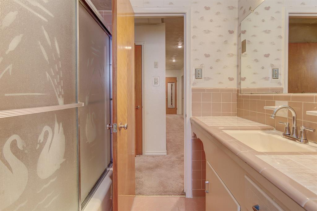 9203 Lindaro Lane Dallas, TX 75228 - Photo 25 of 32 Full bath with wallpapered walls, vanity, combined bath / shower with glass door, tile walls, and wainscoting