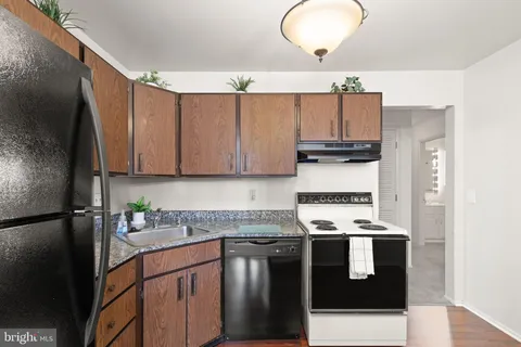 a kitchen with stainless steel appliances granite countertop a refrigerator stove a sink and dishwasher with wooden floor