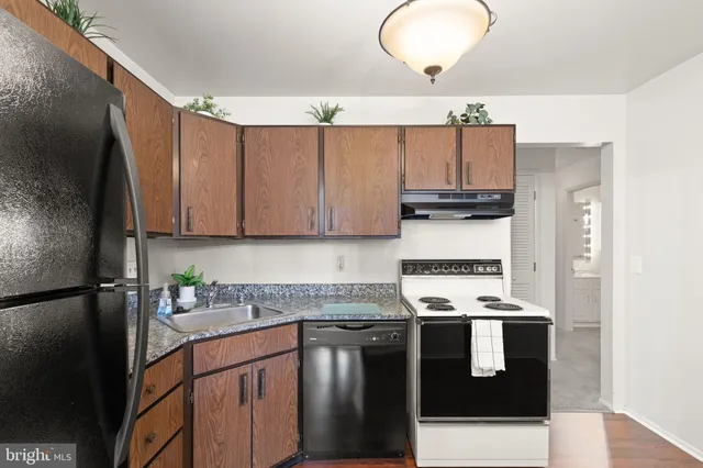 a kitchen with stainless steel appliances granite countertop a refrigerator stove a sink and dishwasher with wooden floor